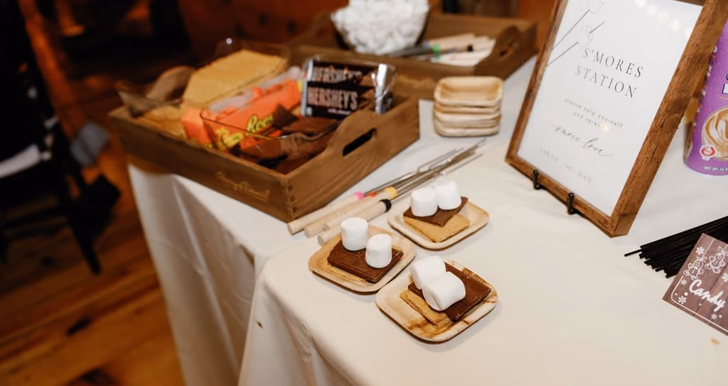 A rustic s'mores station set up on a table at a wedding reception