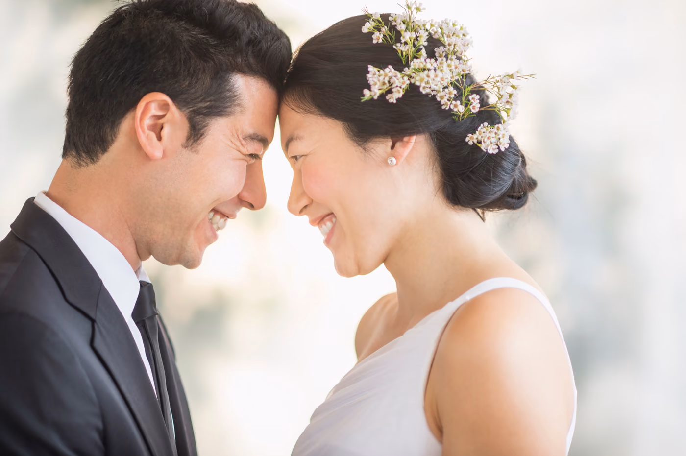 Close-up of a bride and groom smiling with their foreheads touching