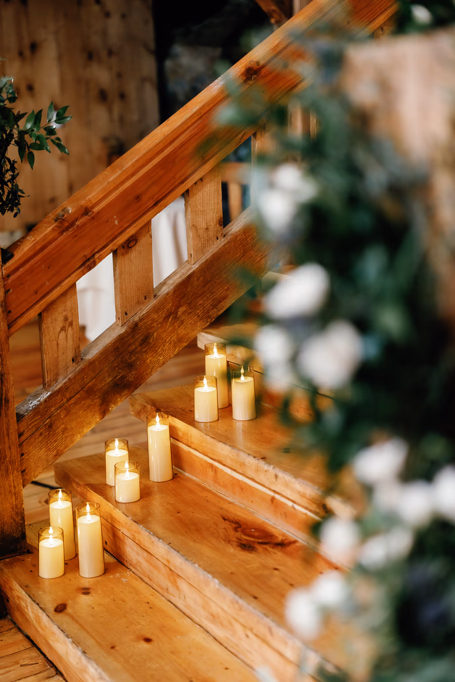 Pillar candles and white flowers lining a wooden staircase