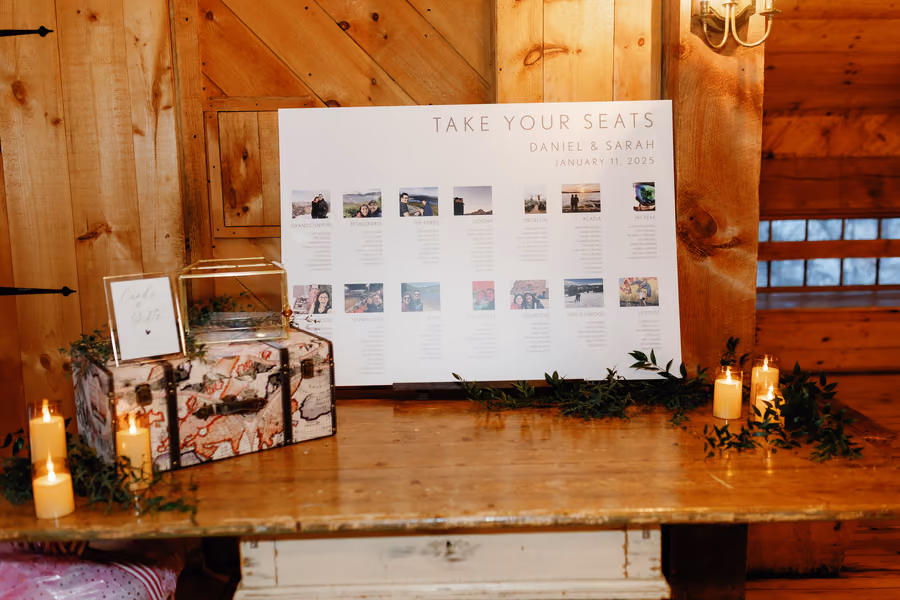 A wedding seating chart display with photographs, candles, and greenery on a wooden table