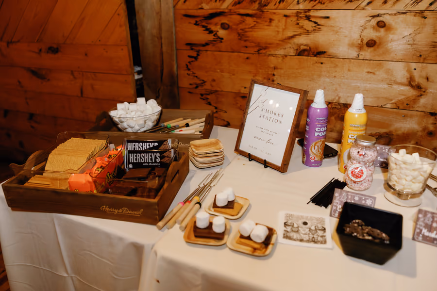 A s'mores dessert bar with marshmallows, chocolate, and toppings on a wooden table