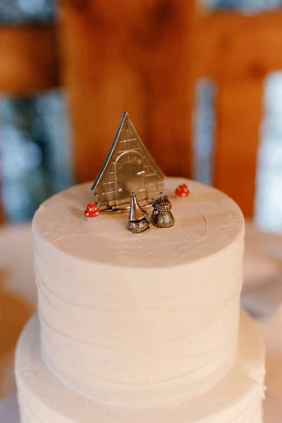 A smooth white wedding cake topped with small gnome figurine cake toppers