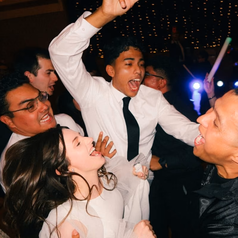 Wedding guests singing and dancing enthusiastically on a crowded dance floor