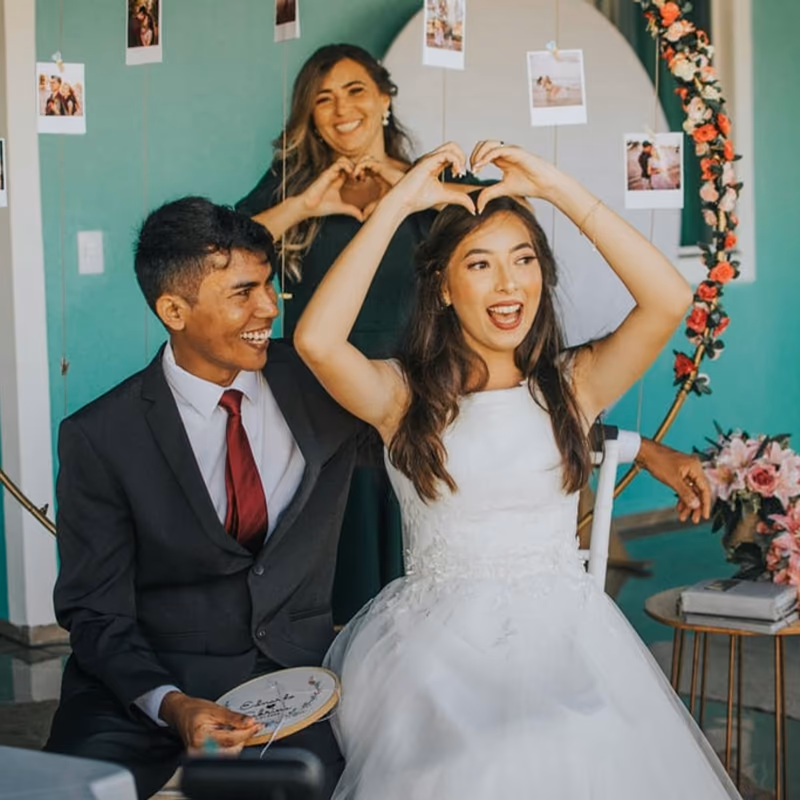 Couple making a heart shape with their hands behind a seated bride and groom