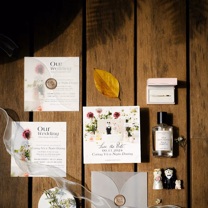 A flat lay of a floral wedding invitation suite, envelopes, and wax seals on a wooden surface